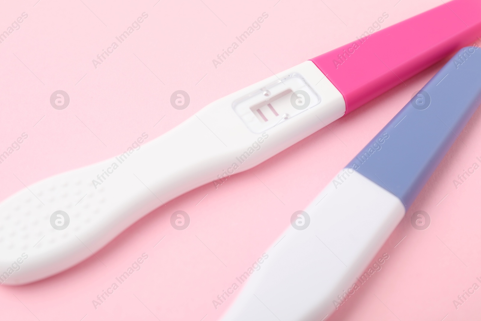 Photo of Two pregnancy tests on pink background, closeup