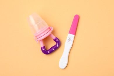 Photo of Pregnancy test and nibbler on pale orange background, top view