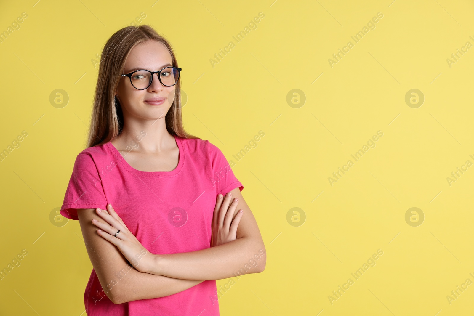 Photo of Portrait of teenage girl in glasses on yellow background, space for text