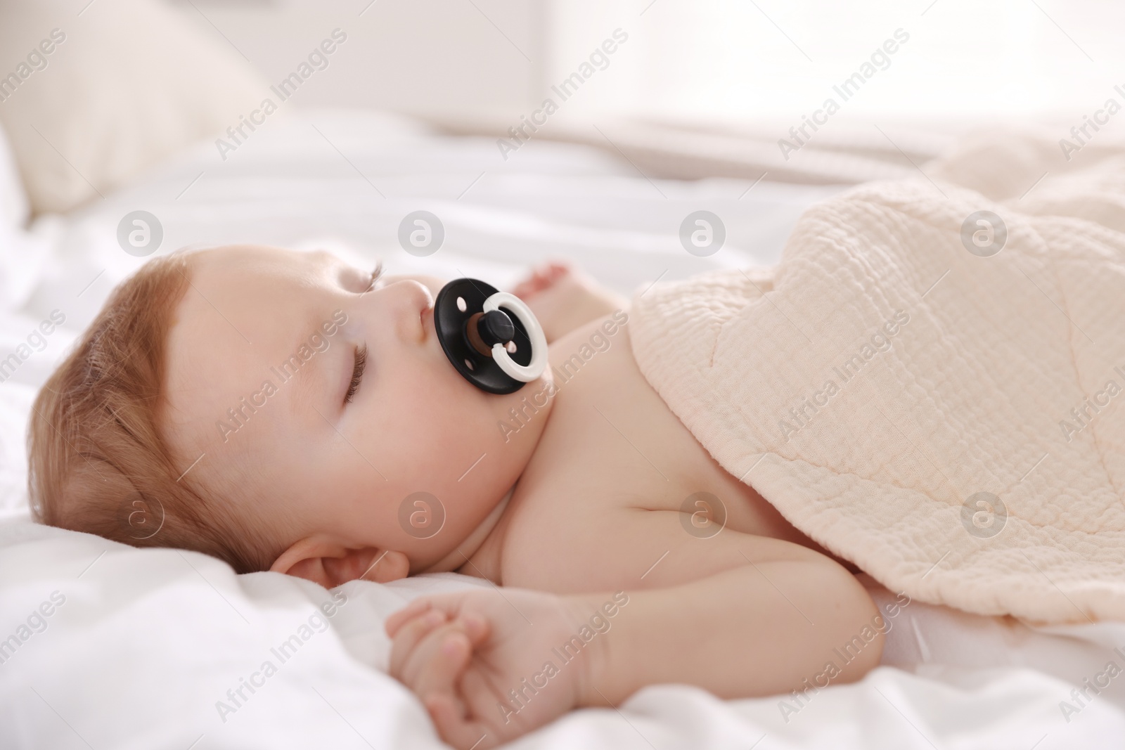 Photo of Cute little baby with pacifier sleeping on bed at home