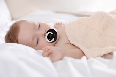 Cute little baby with pacifier sleeping on bed at home