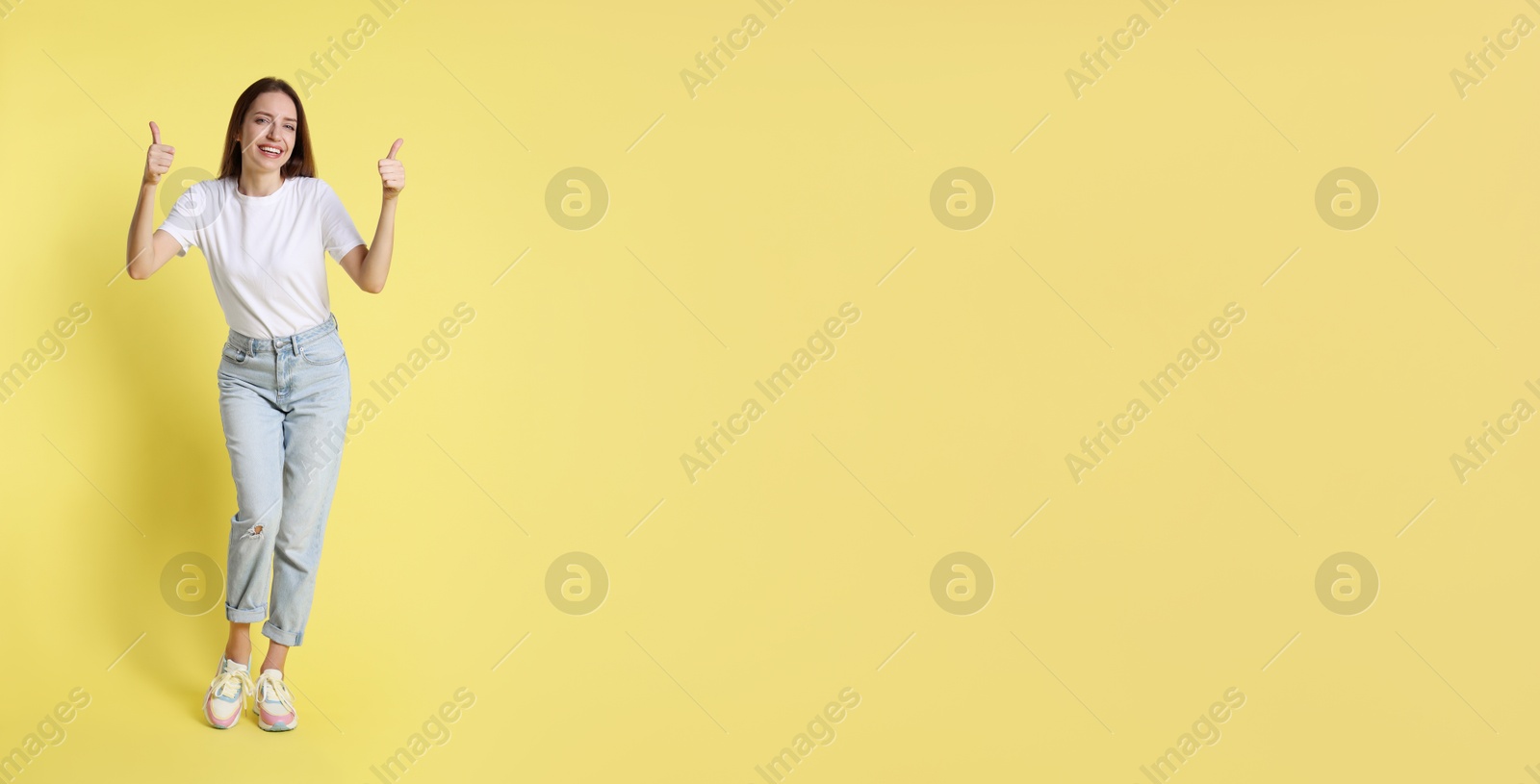 Photo of Happy winner showing thumbs up on yellow background