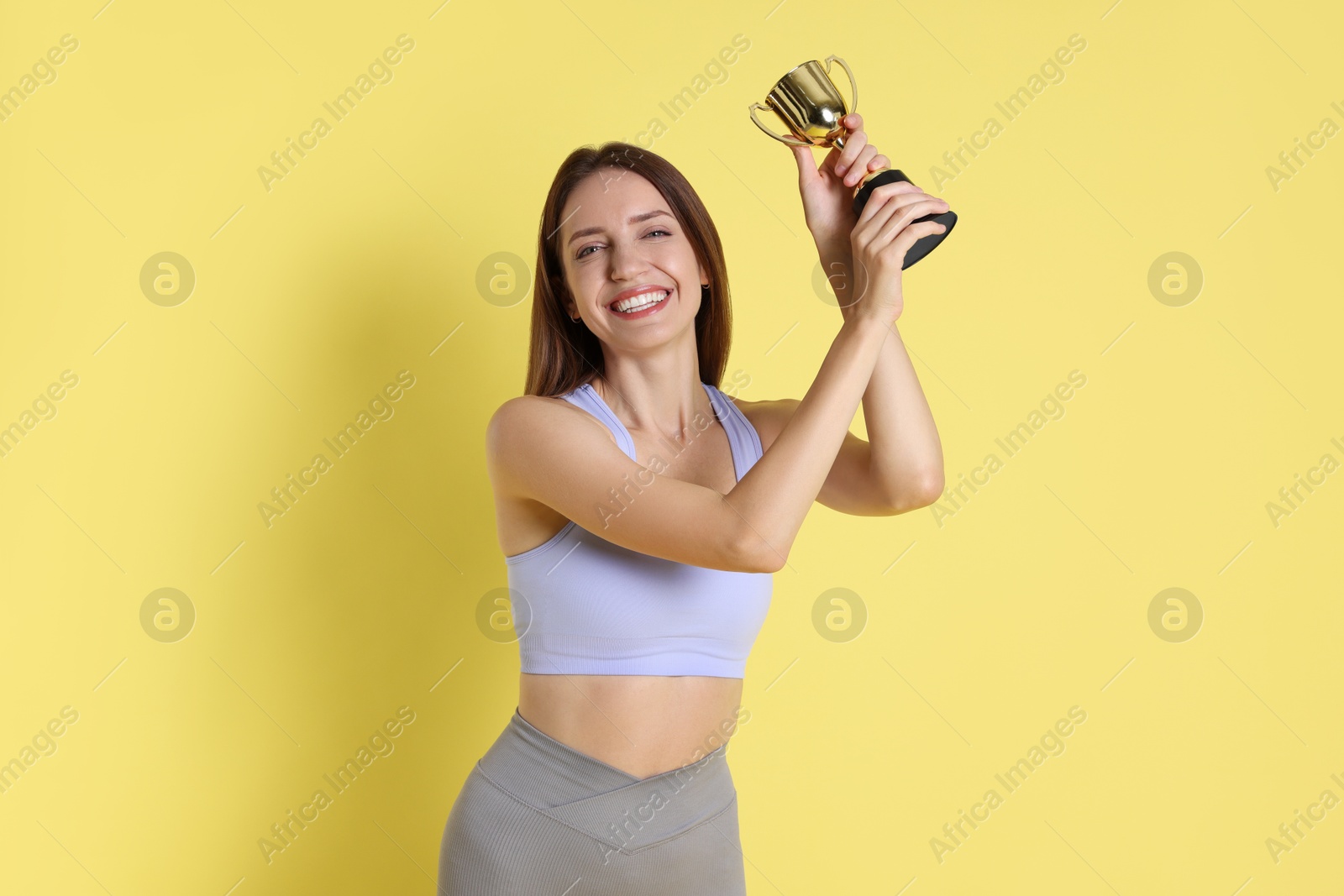 Photo of Happy winner with gold trophy cup on yellow background