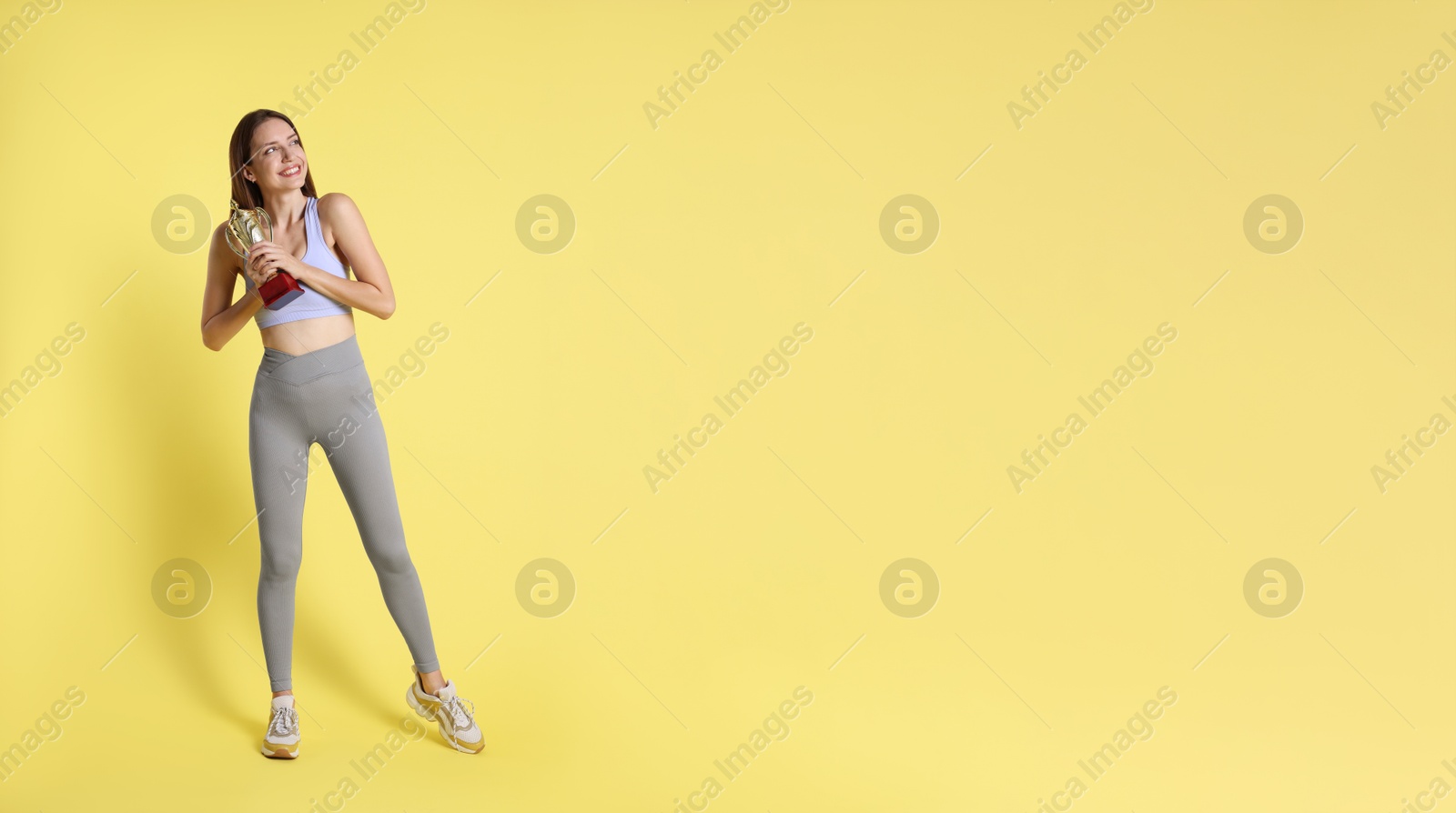 Photo of Happy winner with gold trophy cup on yellow background