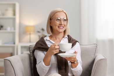 Smiling middle aged woman with cup of hot drink at home