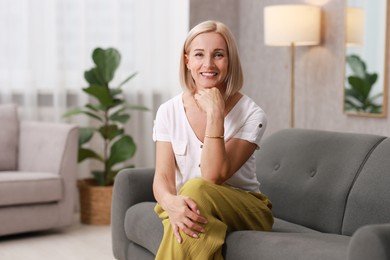 Portrait of smiling middle aged woman on sofa at home