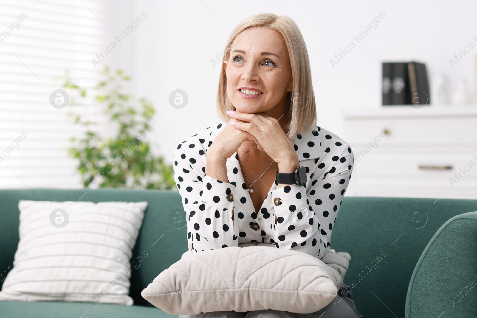 Photo of Portrait of smiling middle aged woman on sofa at home