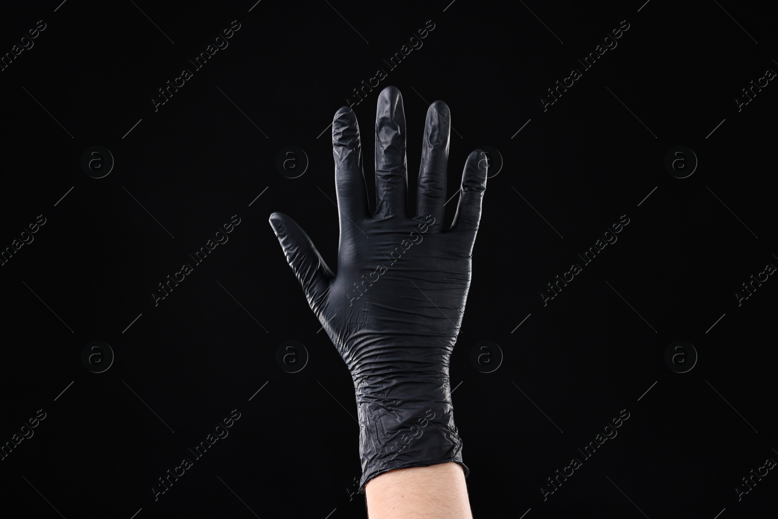 Photo of Man wearing latex glove on black background, closeup