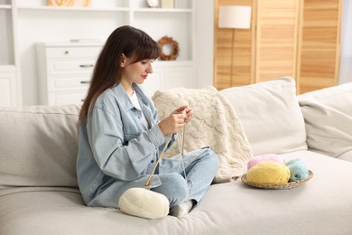 Photo of Beautiful woman knitting on sofa at home