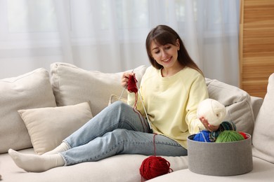 Beautiful woman knitting on sofa at home