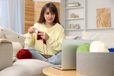 Beautiful woman learning to knit with online course at home