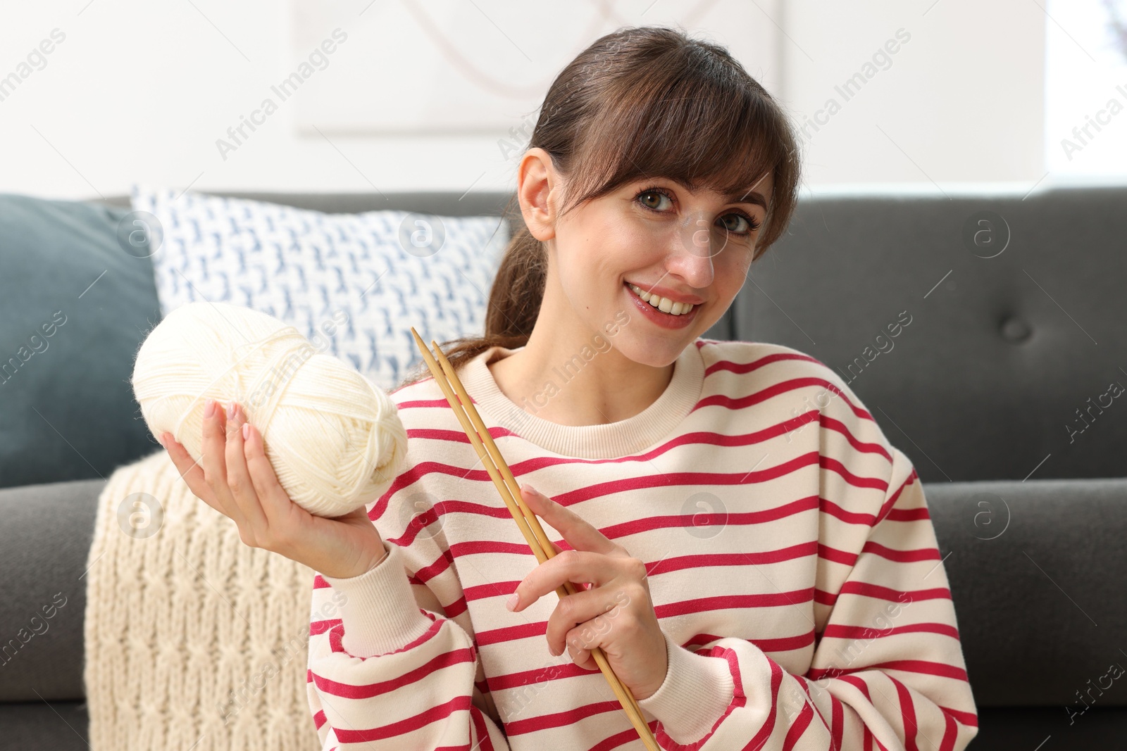 Photo of Beautiful woman with yarn and knitting needles at home