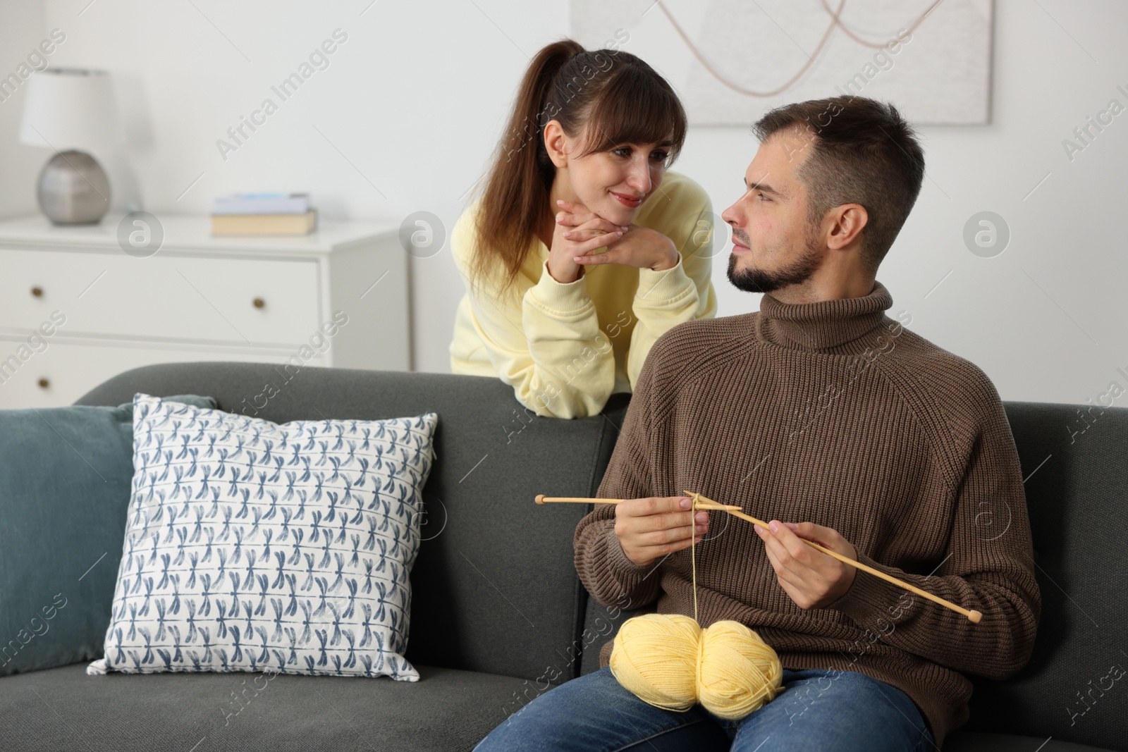 Photo of Woman teaching her boyfriend how to knit at home