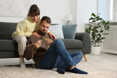 Woman teaching her boyfriend how to knit at home