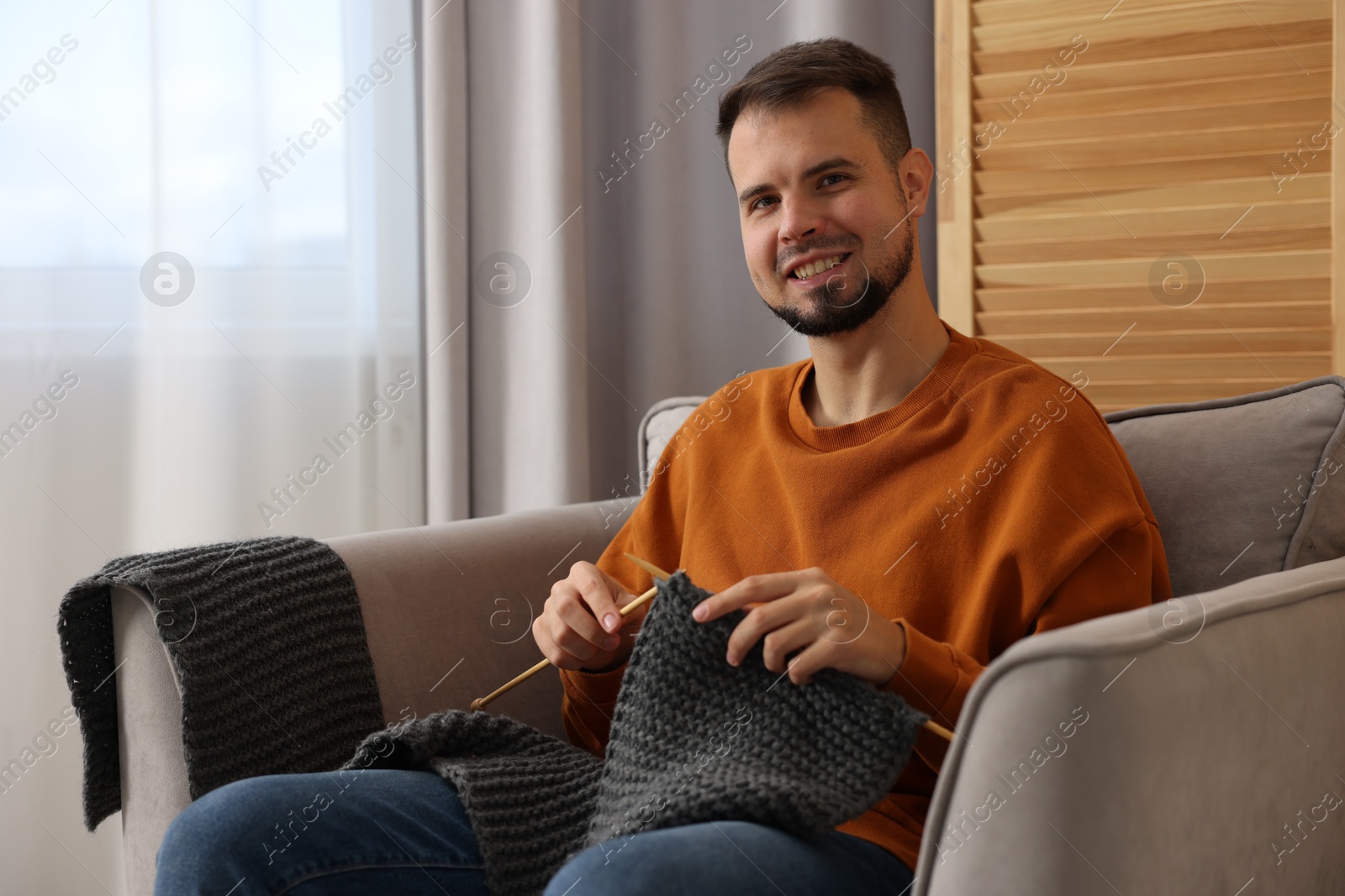 Photo of Man knitting with needles in armchair at home