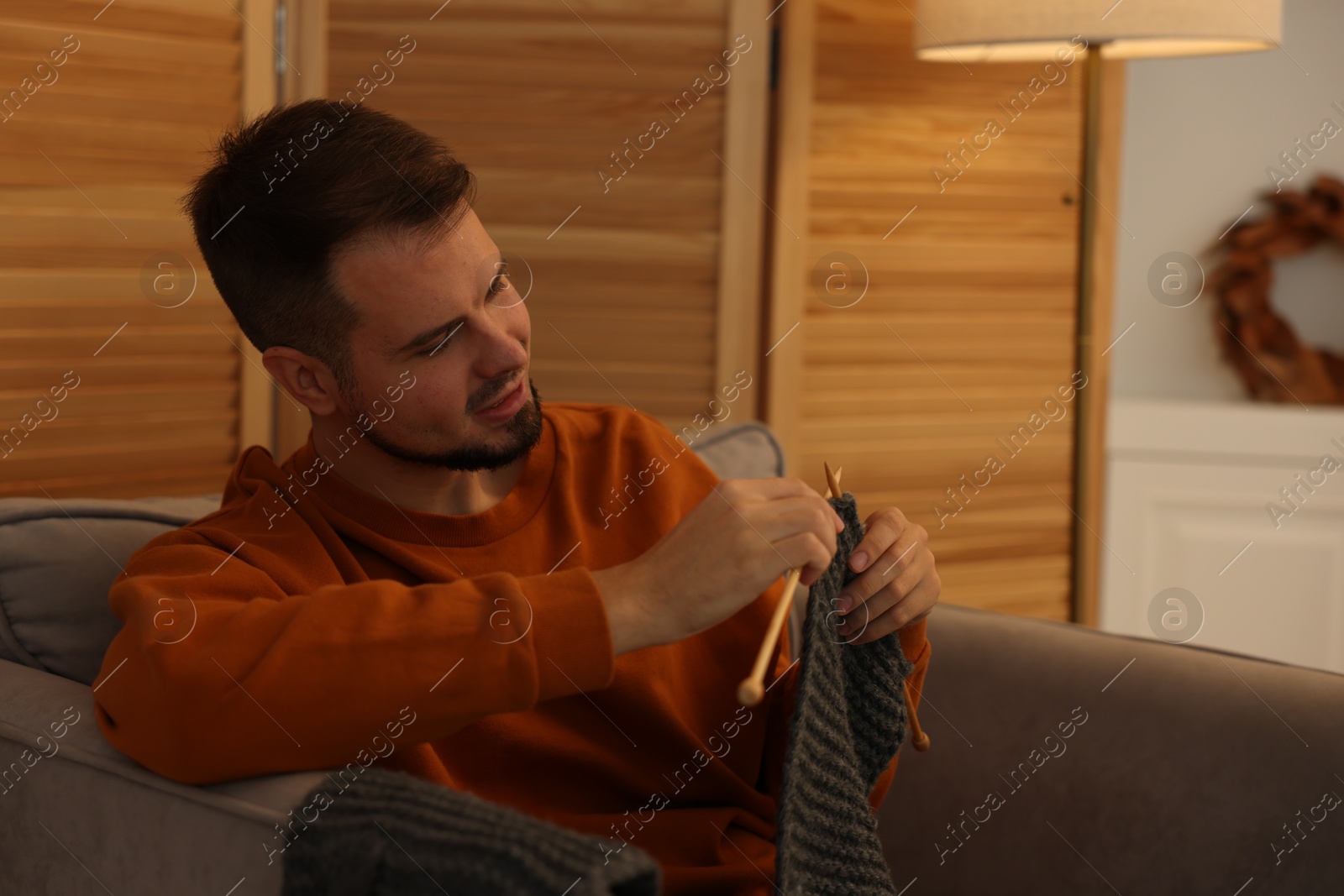 Photo of Man knitting with needles in armchair at home