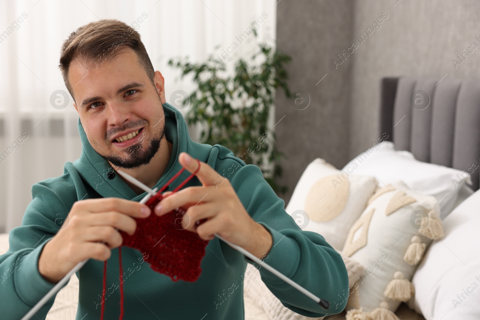 Photo of Happy man knitting with needles at home