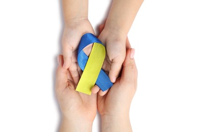 Photo of Woman with child holding yellow and blue ribbon on white background, top view. Down syndrome awareness