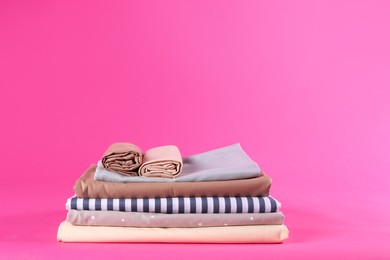 Photo of Stack of clean bed sheets on pink background. Space for text