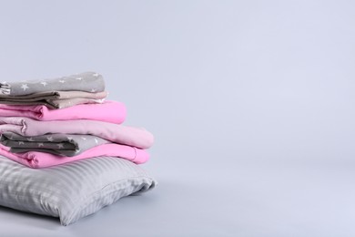 Photo of Stack of clean bed sheets and pillow on white background. Space for text