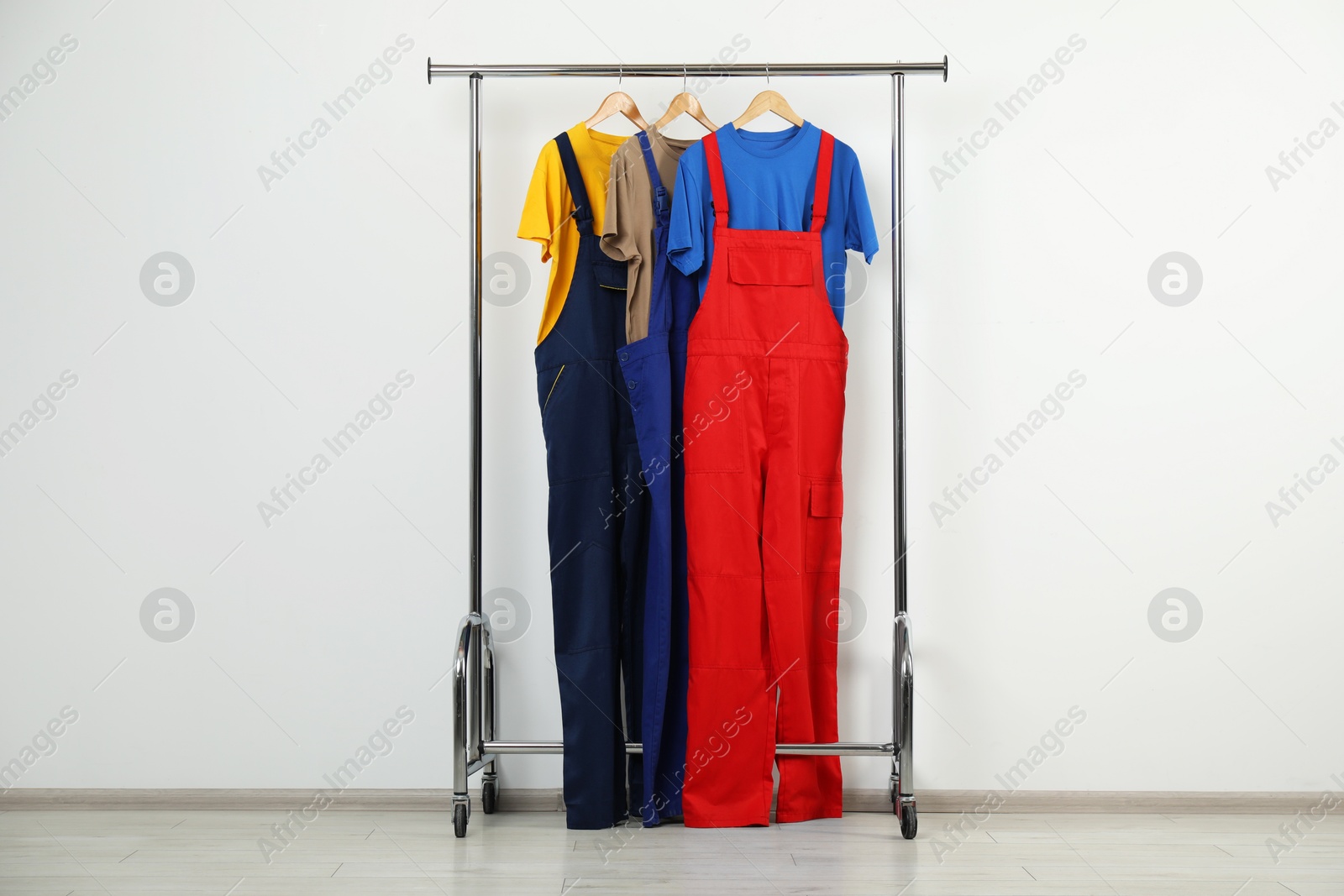 Photo of Workers' uniforms on clothing rack near grey wall indoors