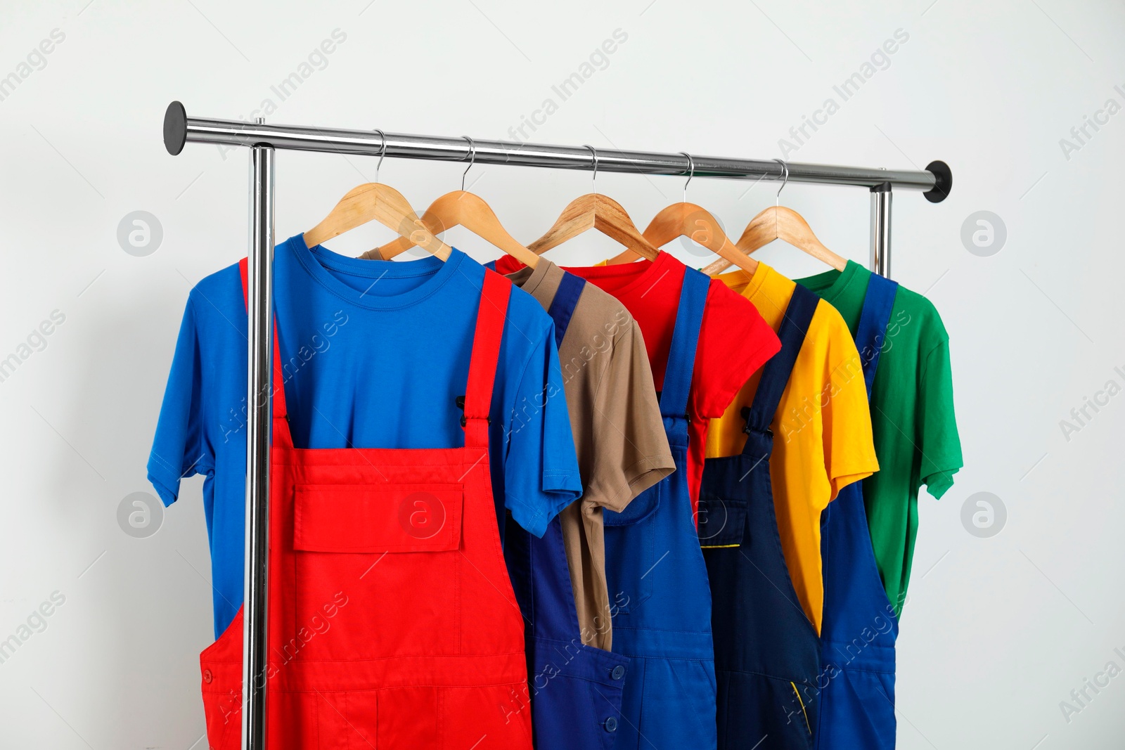 Photo of Workers' uniforms on clothing rack near grey wall indoors