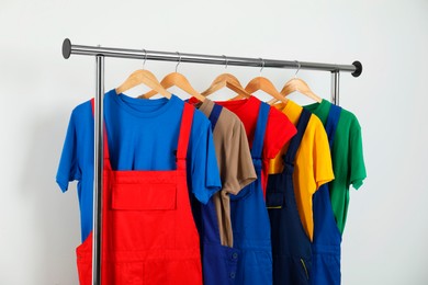 Photo of Workers' uniforms on clothing rack near grey wall indoors