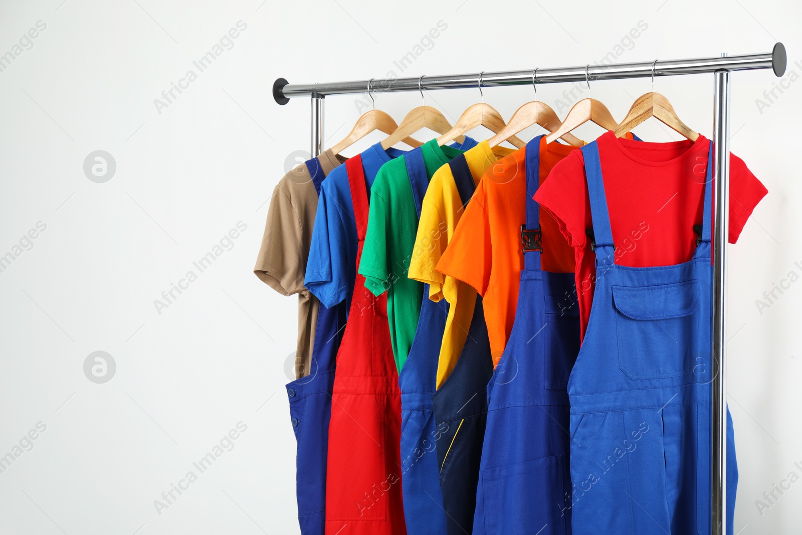 Photo of Workers' uniforms on clothing rack near grey wall indoors. Space for text