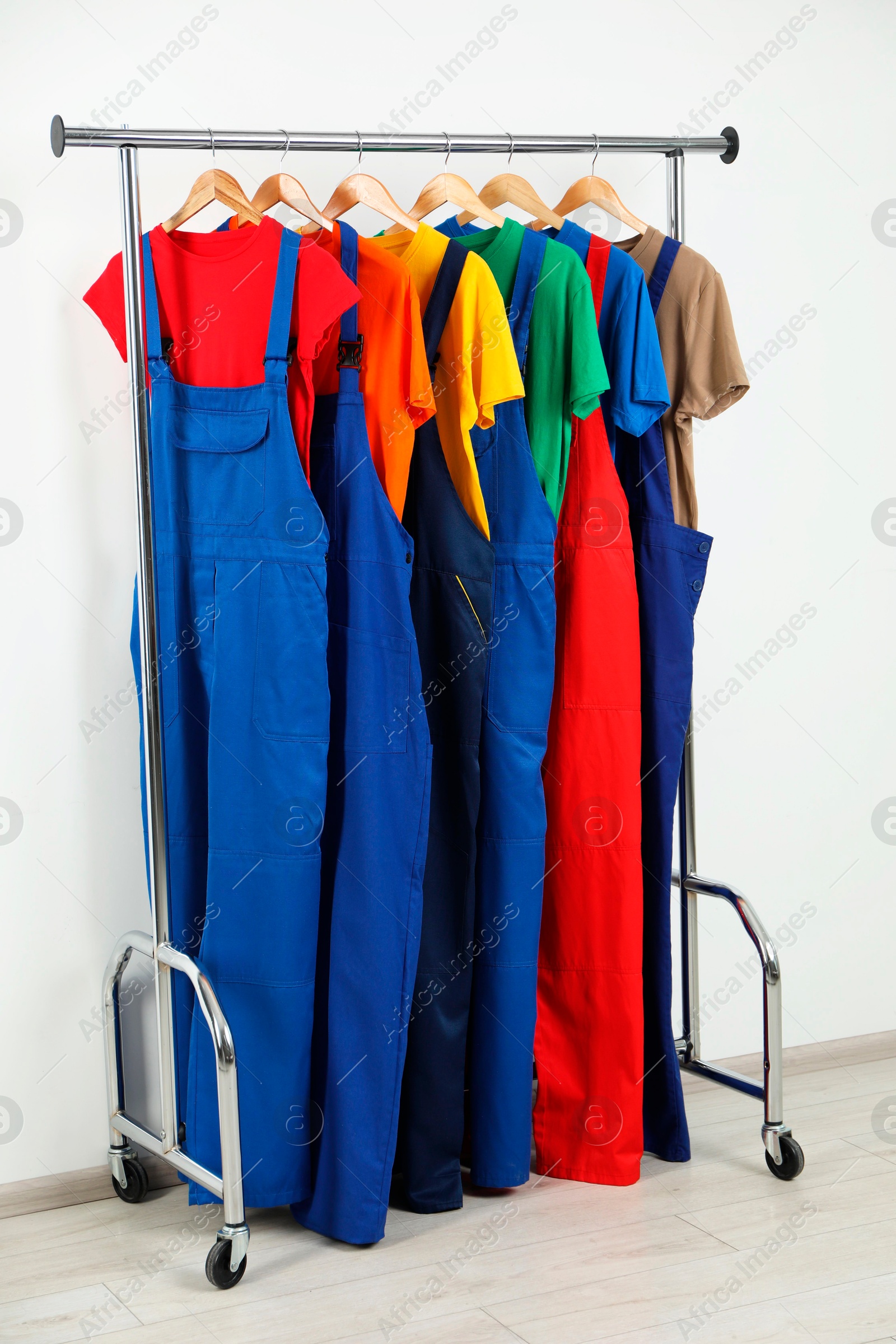 Photo of Workers' uniforms on clothing rack near grey wall indoors