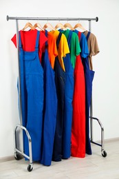 Photo of Workers' uniforms on clothing rack near grey wall indoors