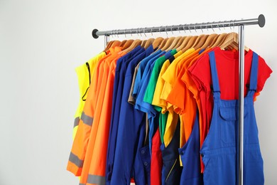 Photo of Workers' uniforms on clothing rack near grey wall indoors. Space for text