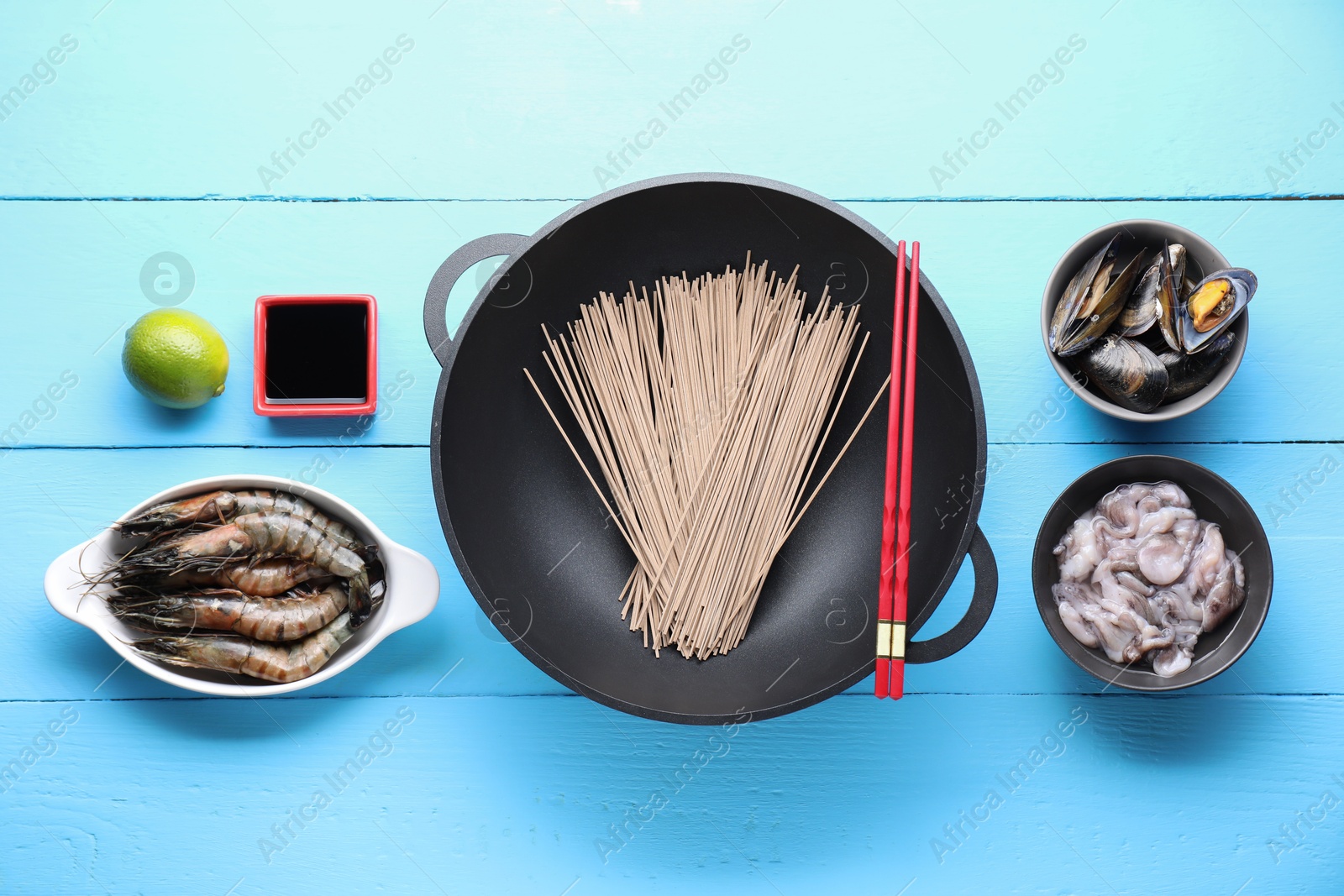 Photo of Different ingredients for wok on light blue wooden table, flat lay