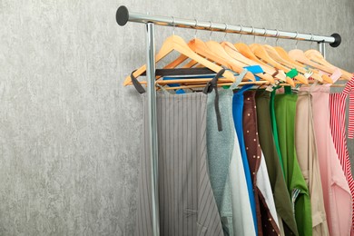 Photo of Many chef's aprons on clothing rack near light grey wall, space for text