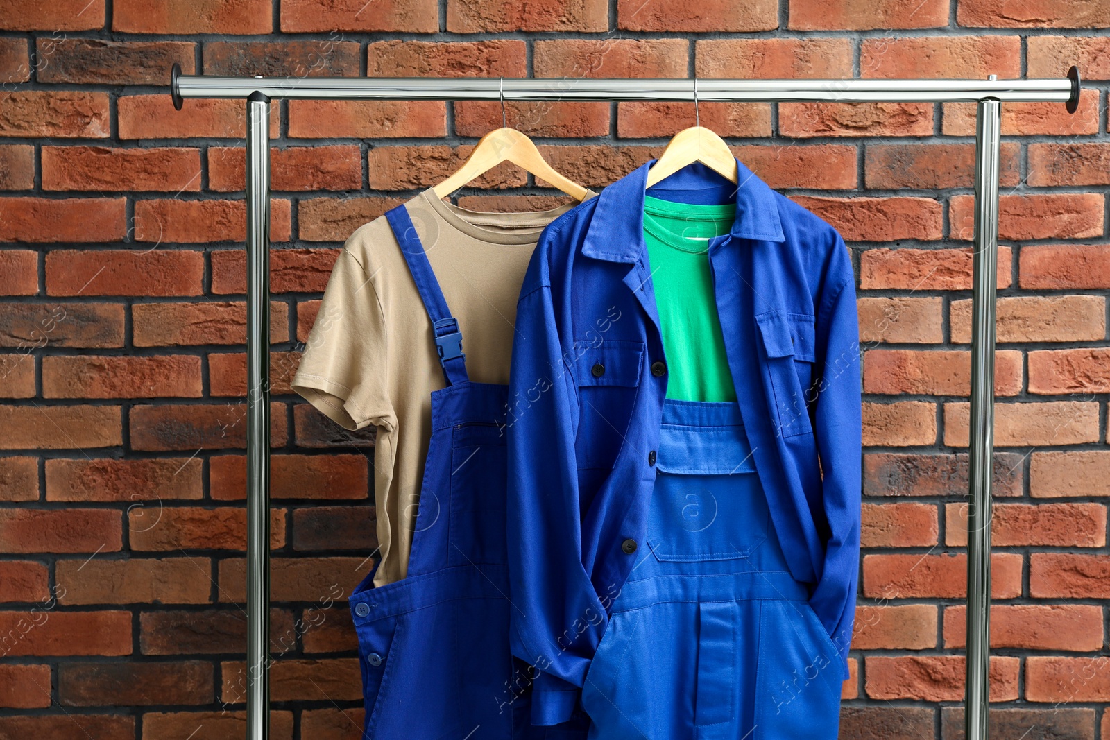 Photo of Workers' uniforms on clothing rack near brick wall