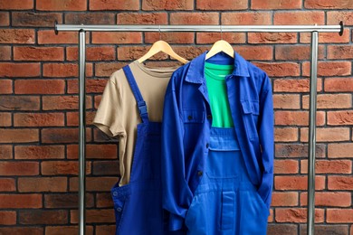 Photo of Workers' uniforms on clothing rack near brick wall