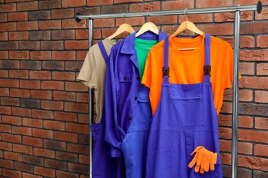 Photo of Different workers' uniforms on clothing rack near brick wall