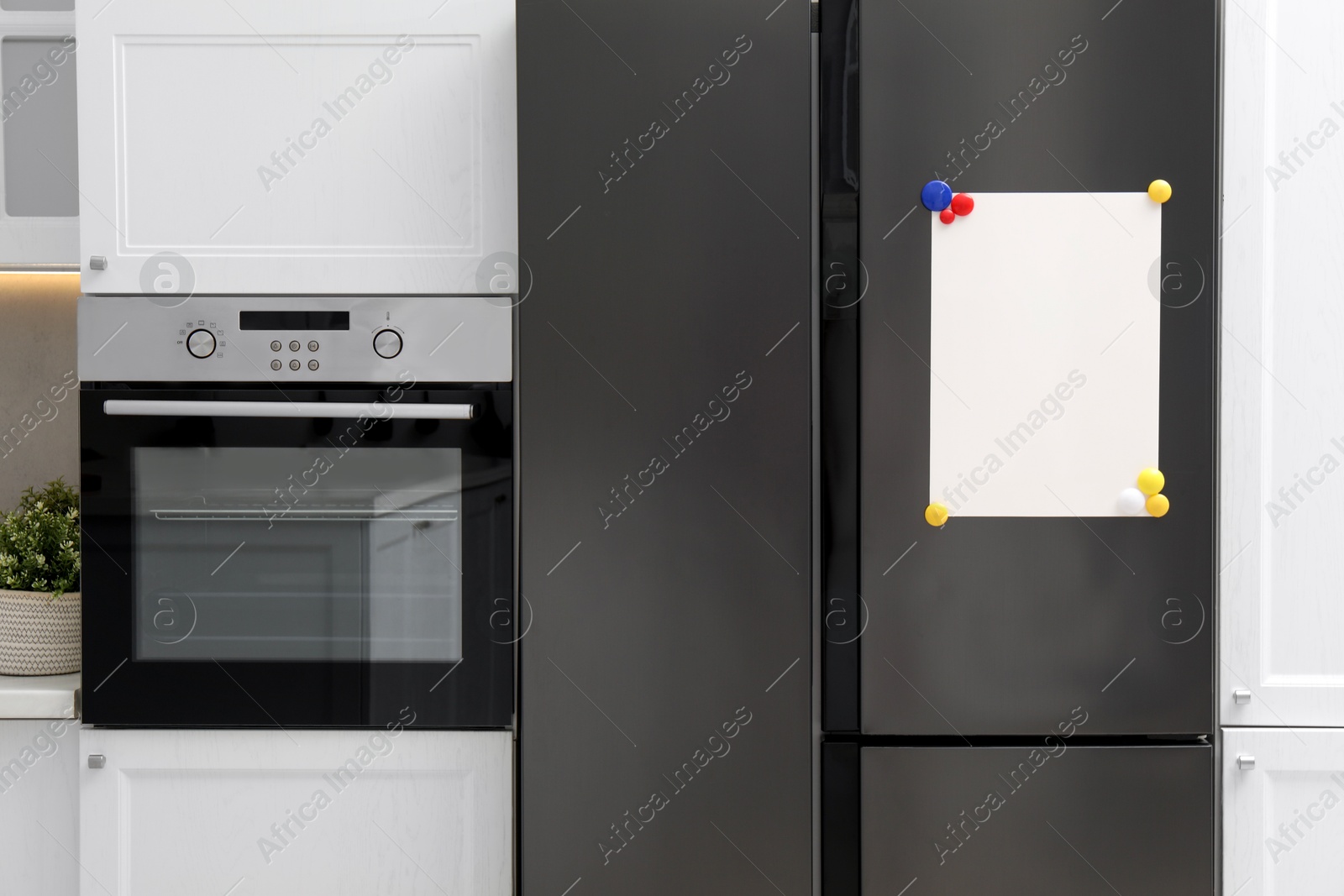 Photo of Blank note board with magnets on refrigerator in kitchen. Mockup for design