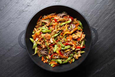 Stir-fry sea food in wok on grey textured table, top view