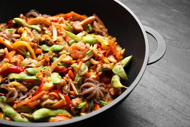 Photo of Stir-fry sea food in wok on grey table, closeup