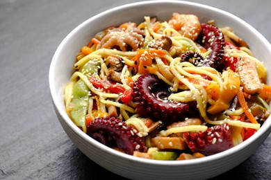 Stir-fry noodles with sea food in bowl on grey table, closeup