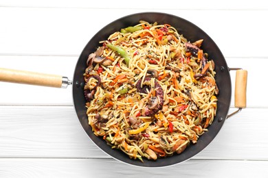 Stir-fry noodles with sea food and vegetables in wok on white wooden table, top view