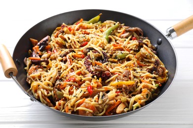 Photo of Stir-fry noodles with sea food and vegetables in wok on white wooden table, closeup