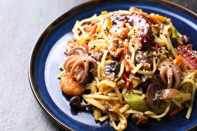 Photo of Stir-fry noodles with sea food and vegetables on dark textured table, closeup