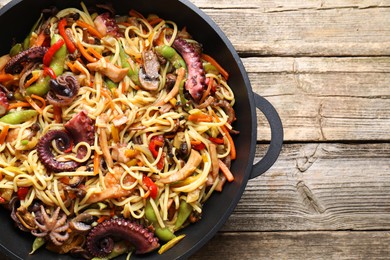 Photo of Stir-fry noodles with sea food and vegetables in wok on wooden table, top view. Space for text