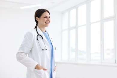 Smiling healthcare worker with stethoscope in hospital, space for text