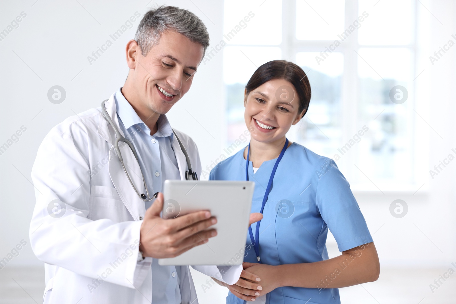 Photo of Smiling healthcare workers with tablet in hospital