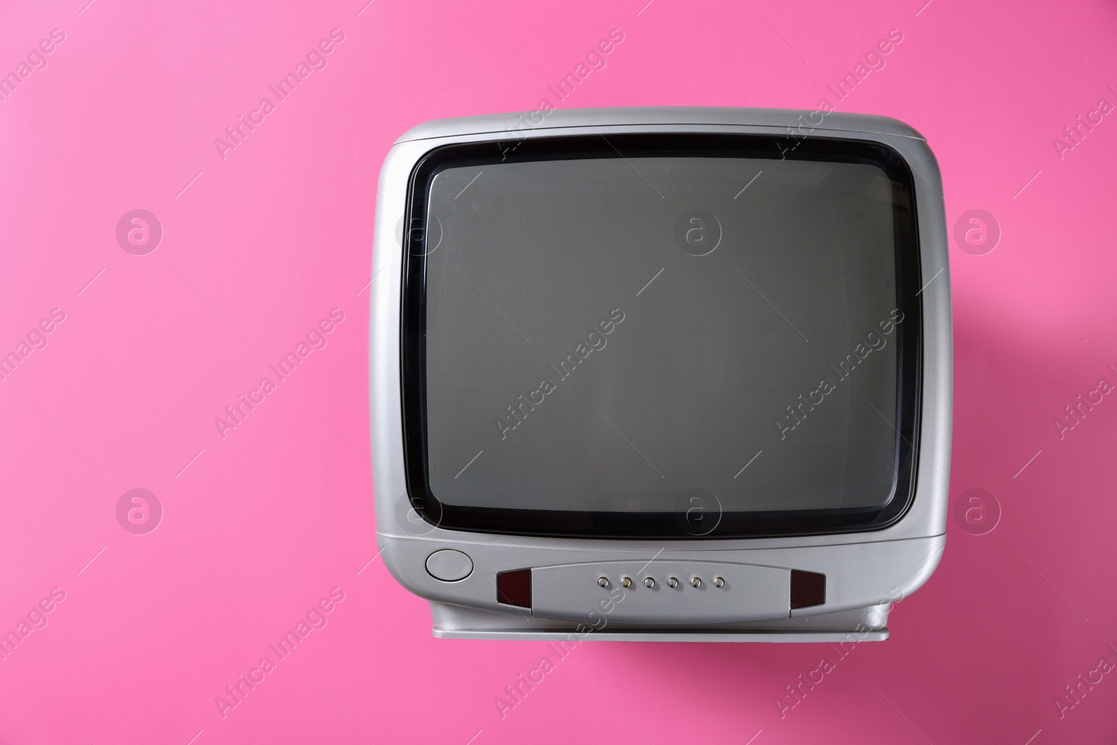 Photo of Retro tv set on pink background, top view. Space for text