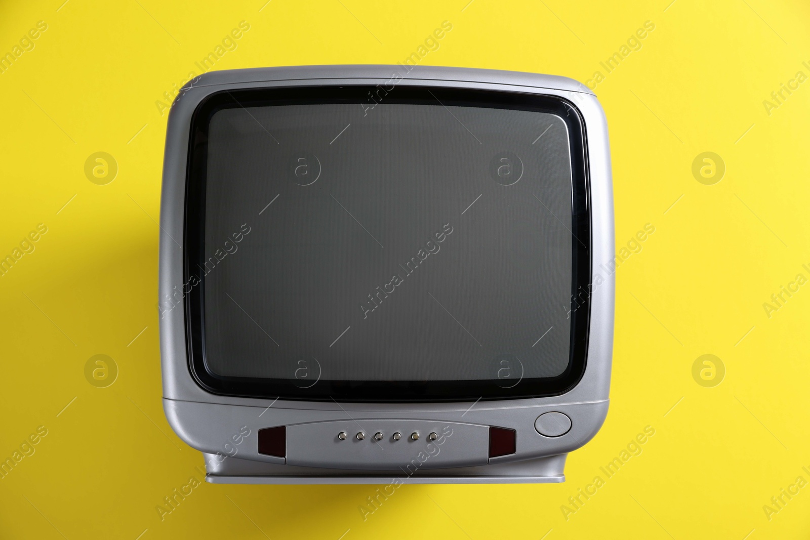 Photo of Retro tv set on yellow background, top view