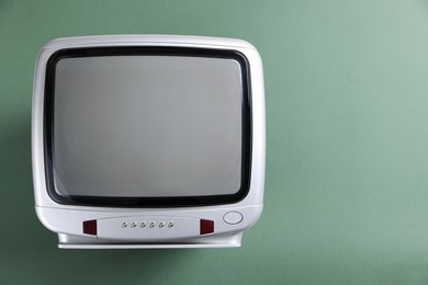 Photo of Retro tv set on green background, top view. Space for text