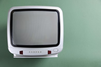 Photo of Retro tv set on green background, top view. Space for text